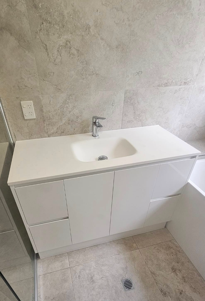 White bathroom vanity with a sink against a textured wall.