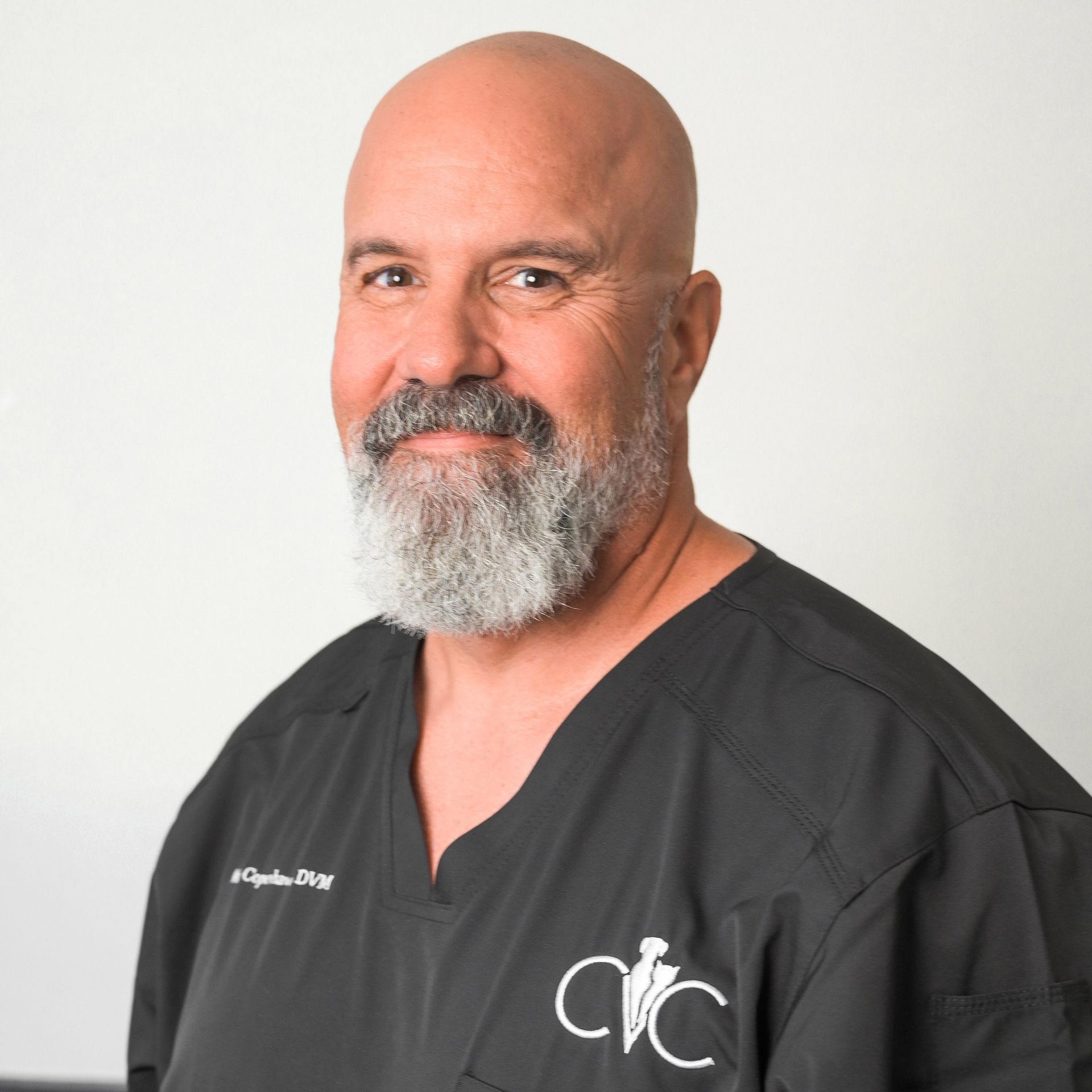 a bald man with a beard is wearing a black scrub top that says cvc. Dr. Mike Copenhaver