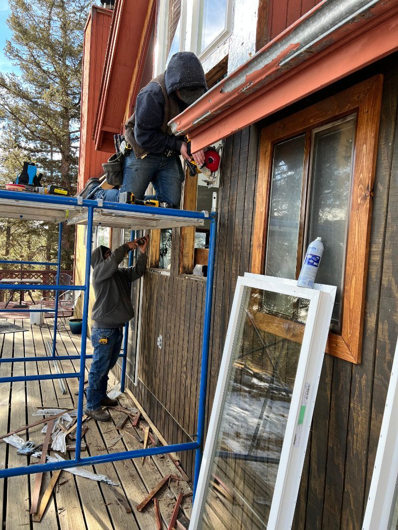 A man is standing on a scaffolding working on a window on the side of a building.