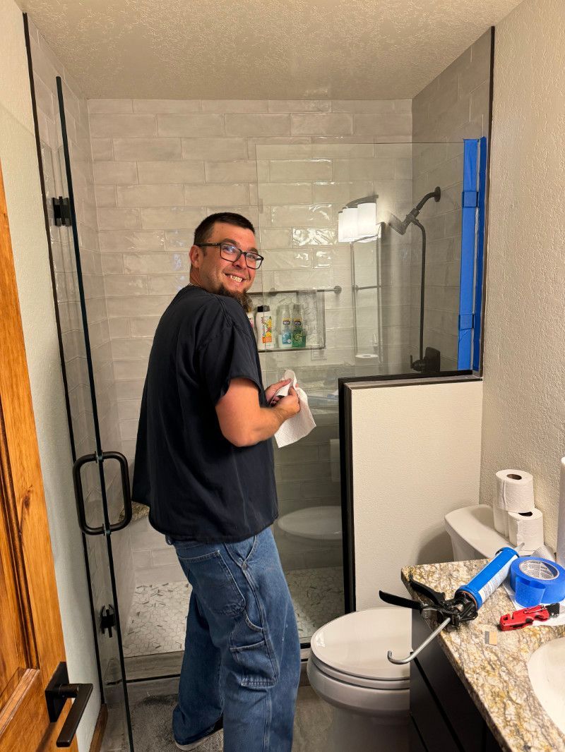 A man is standing in a bathroom next to a toilet.