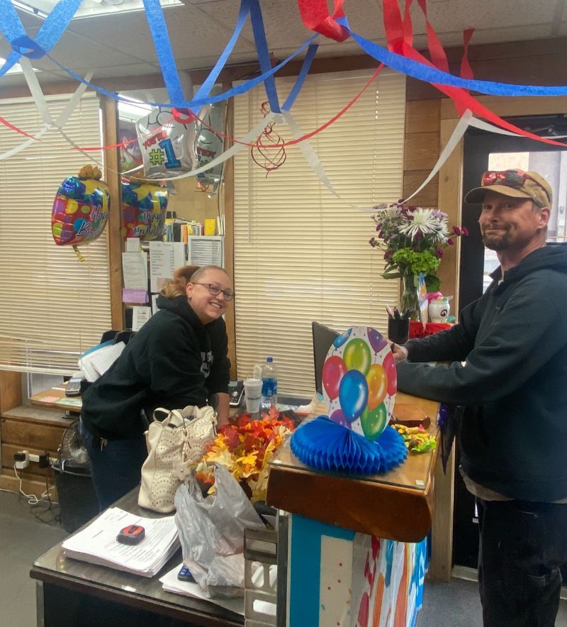 A man and a woman are standing in a room decorated with balloons and streamers