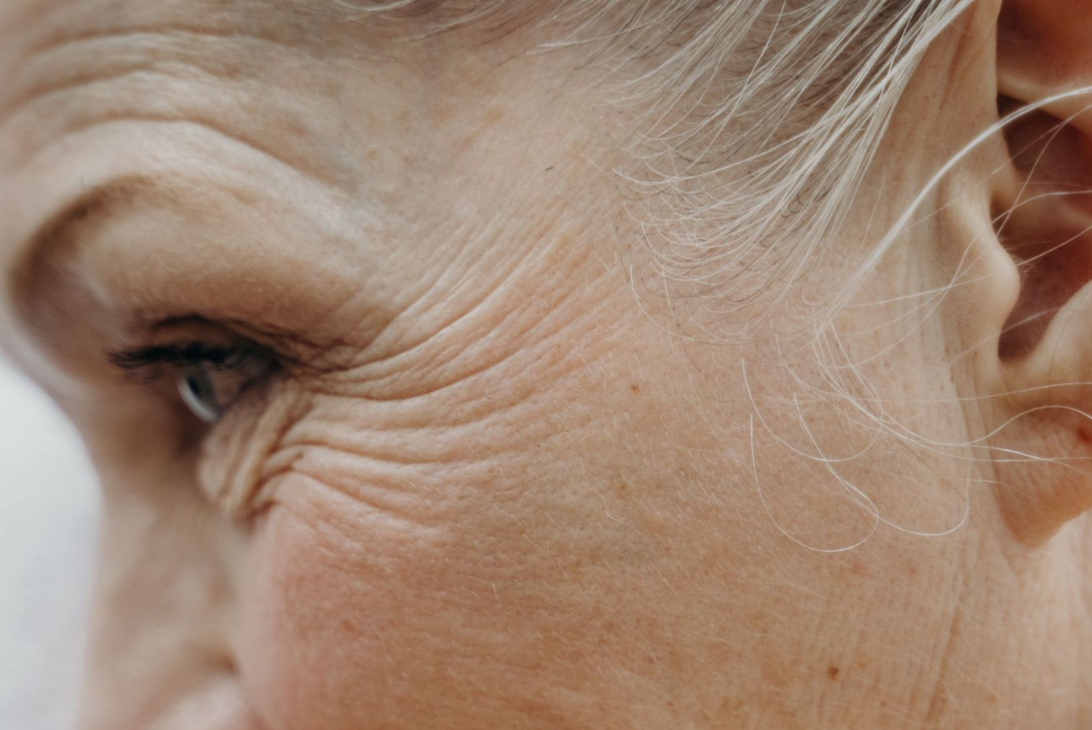 Close-up of a smiling eye and cheek with fine wrinkles in soft natural light