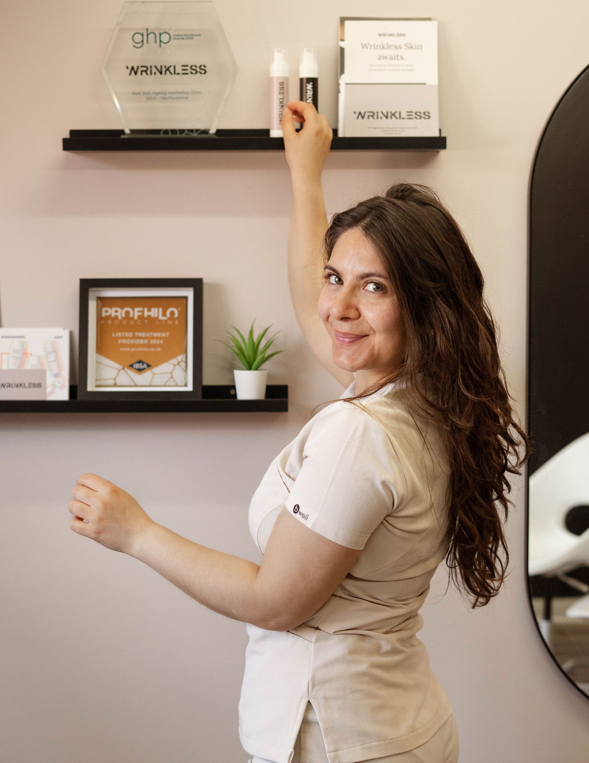Woman reaching for a bottle on a shelf; in a well-lit medical aesthetic clinic.