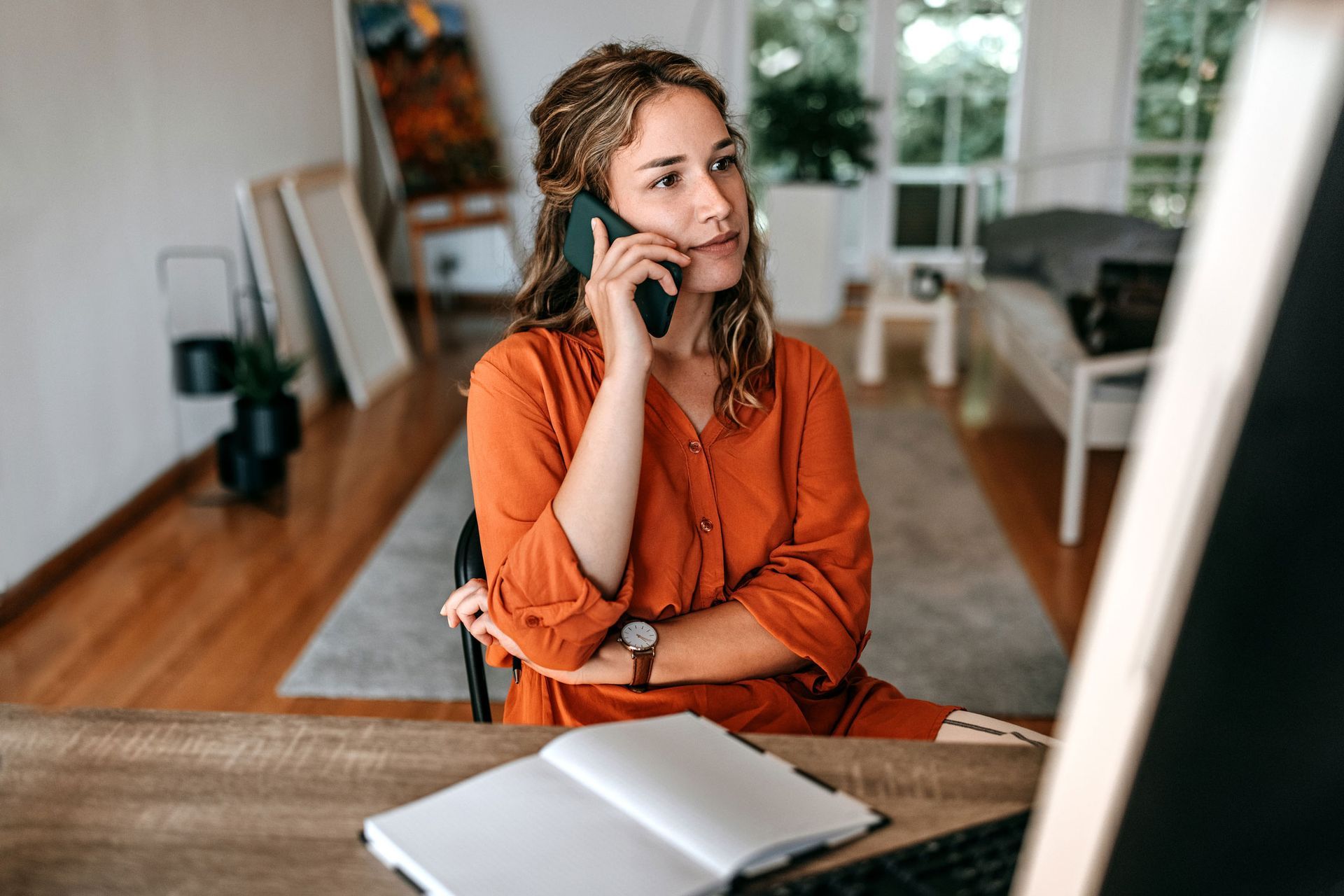 A woman is sitting at a desk talking on a cell phone.