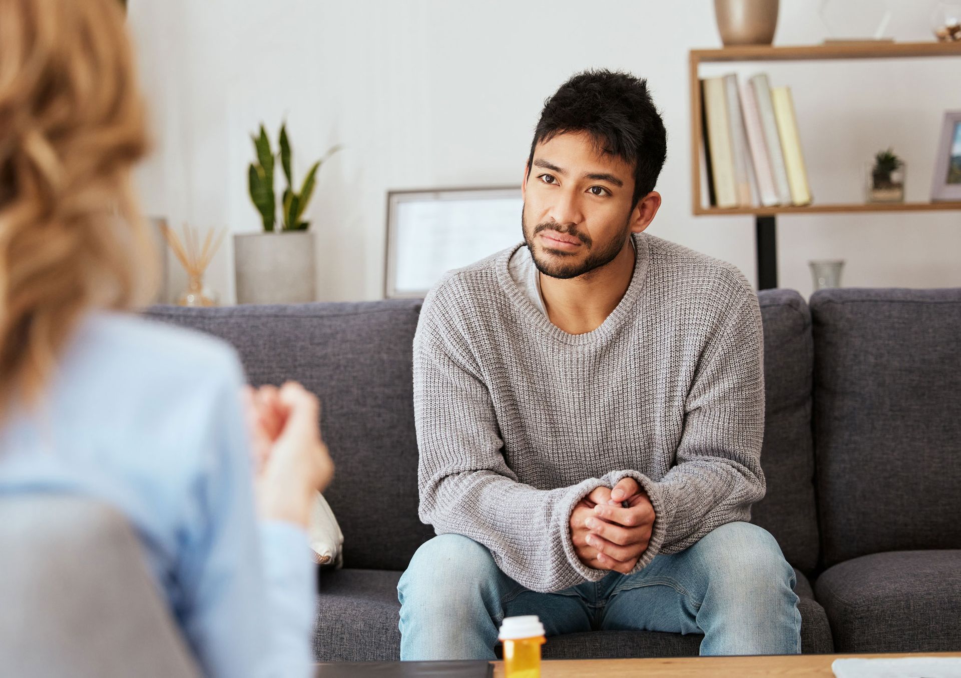 A man is sitting on a couch talking to a woman.