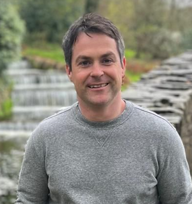 A man in a suit and white shirt is smiling for the camera.