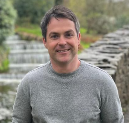 A man in a suit and white shirt is smiling for the camera.