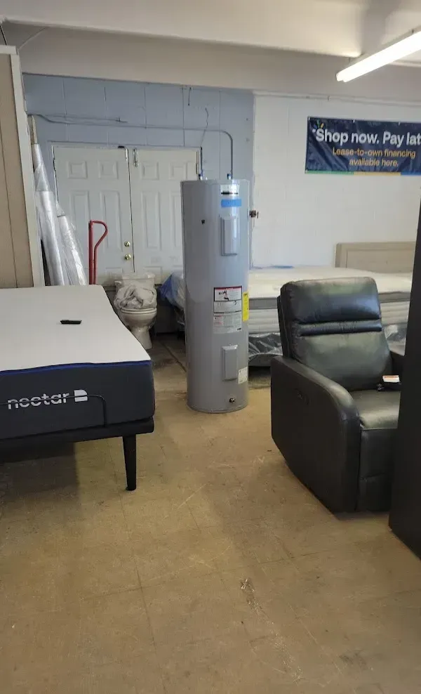 Furniture store showroom with a mattress, gray recliner, and water heater display indoors