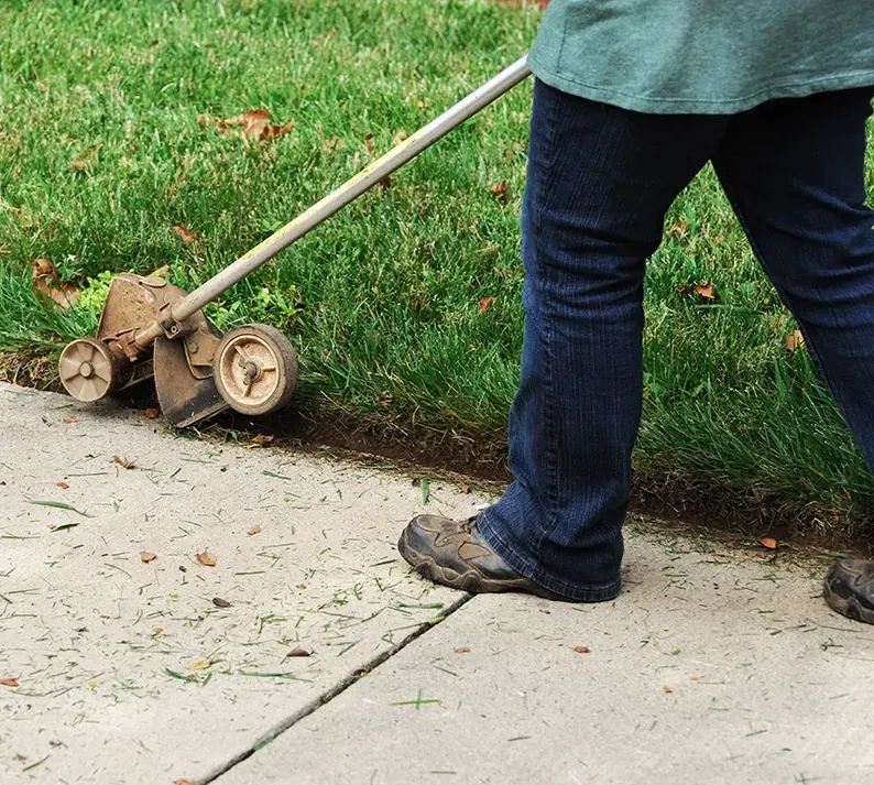 A Person in Blue Jeans Uses a Wheeled Lawn Edger — Your Garden in Charnwood, ACT
