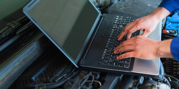 A person is typing on a laptop computer in a garage.