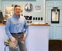 A man is standing in front of a counter in a restaurant.