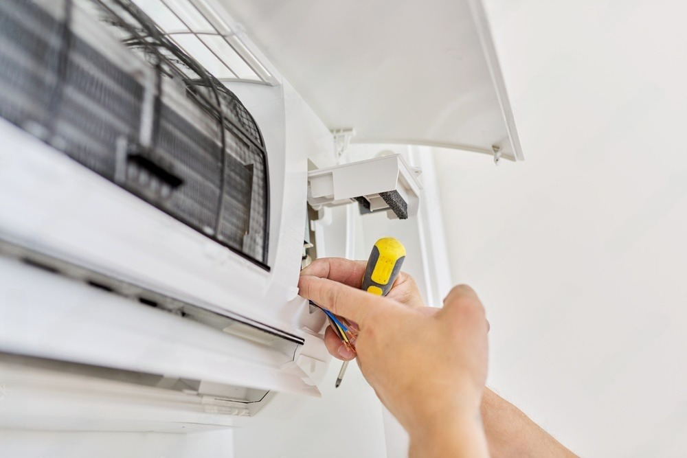 a person is fixing an air conditioner with a screwdriver .