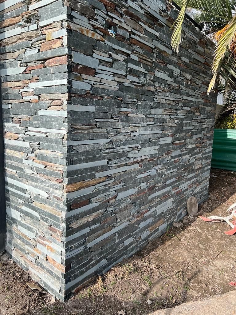 Un gran muro de piedra con una palmera al fondo.