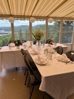 Table à manger formelle dressée pour une célébration,compositions florales et une vue panoramique sur l'extérieur.