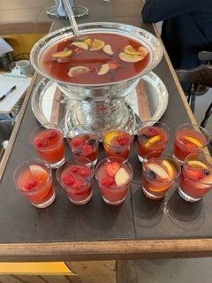 Bol à punch et verres individuels de punch aux fruits sur un comptoir, avec des tranches de fruits et des baies.