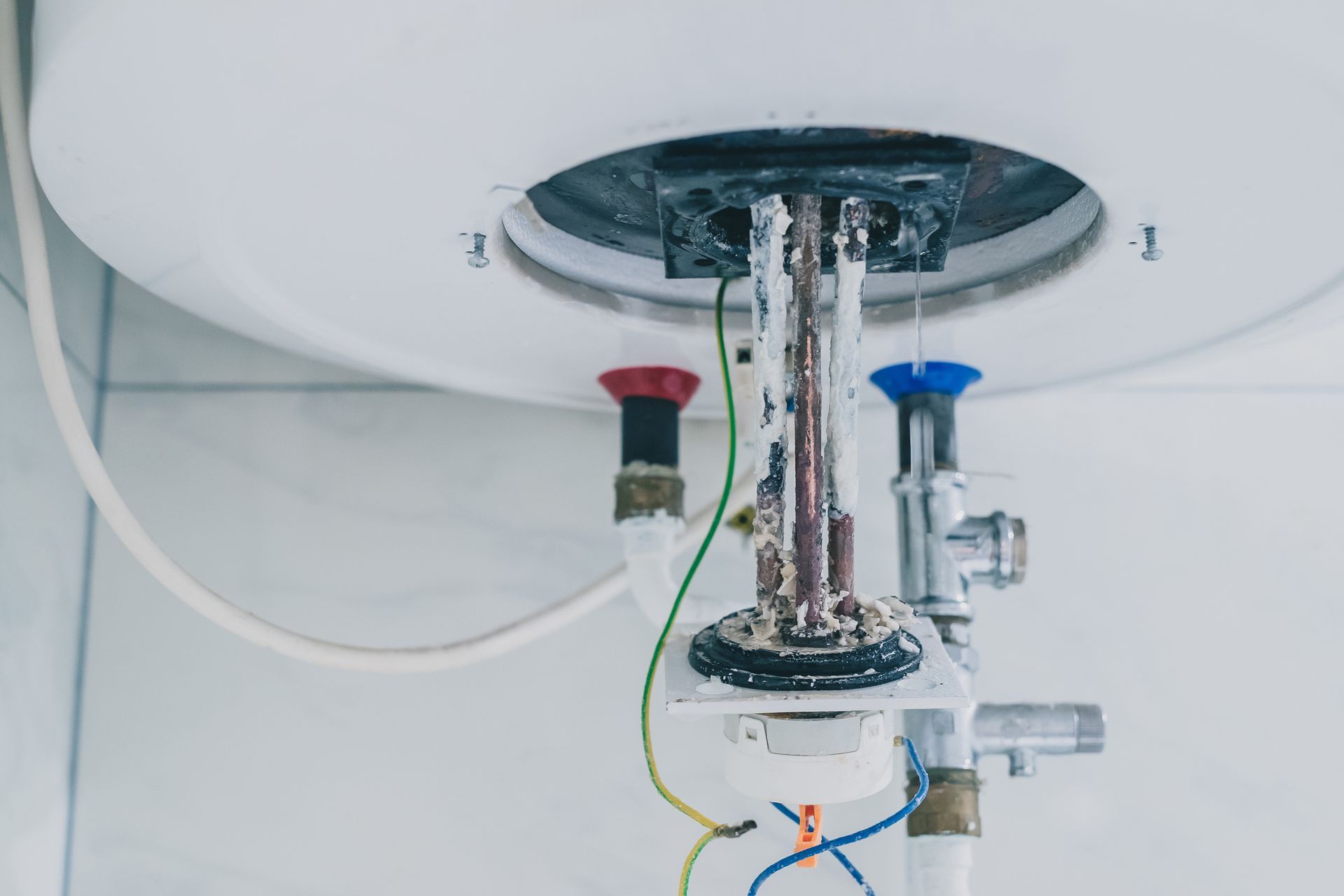 Water heater heating element covered in thick mineral scale buildup from hard water.