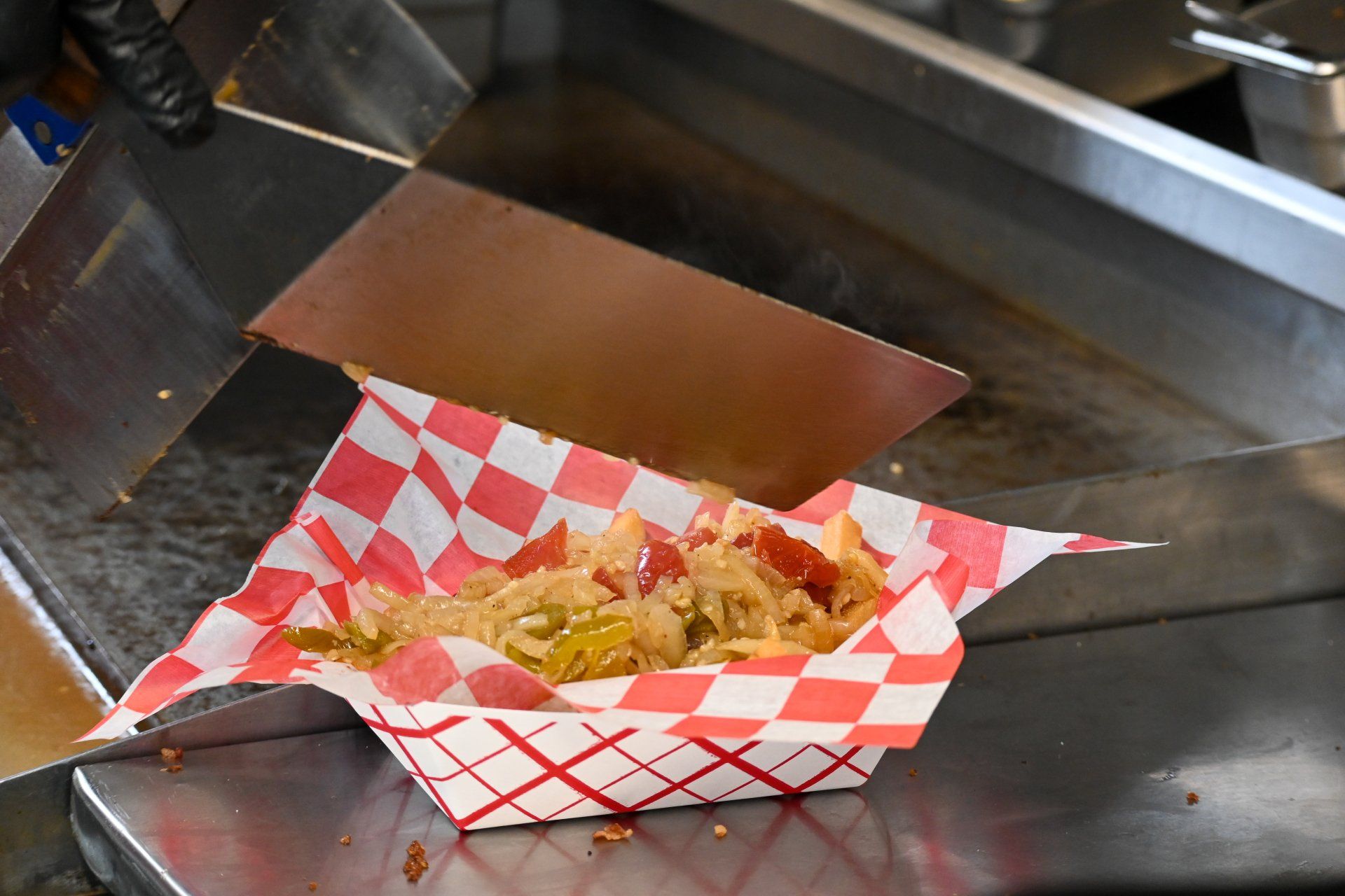 A paper container filled with food is sitting on a counter.