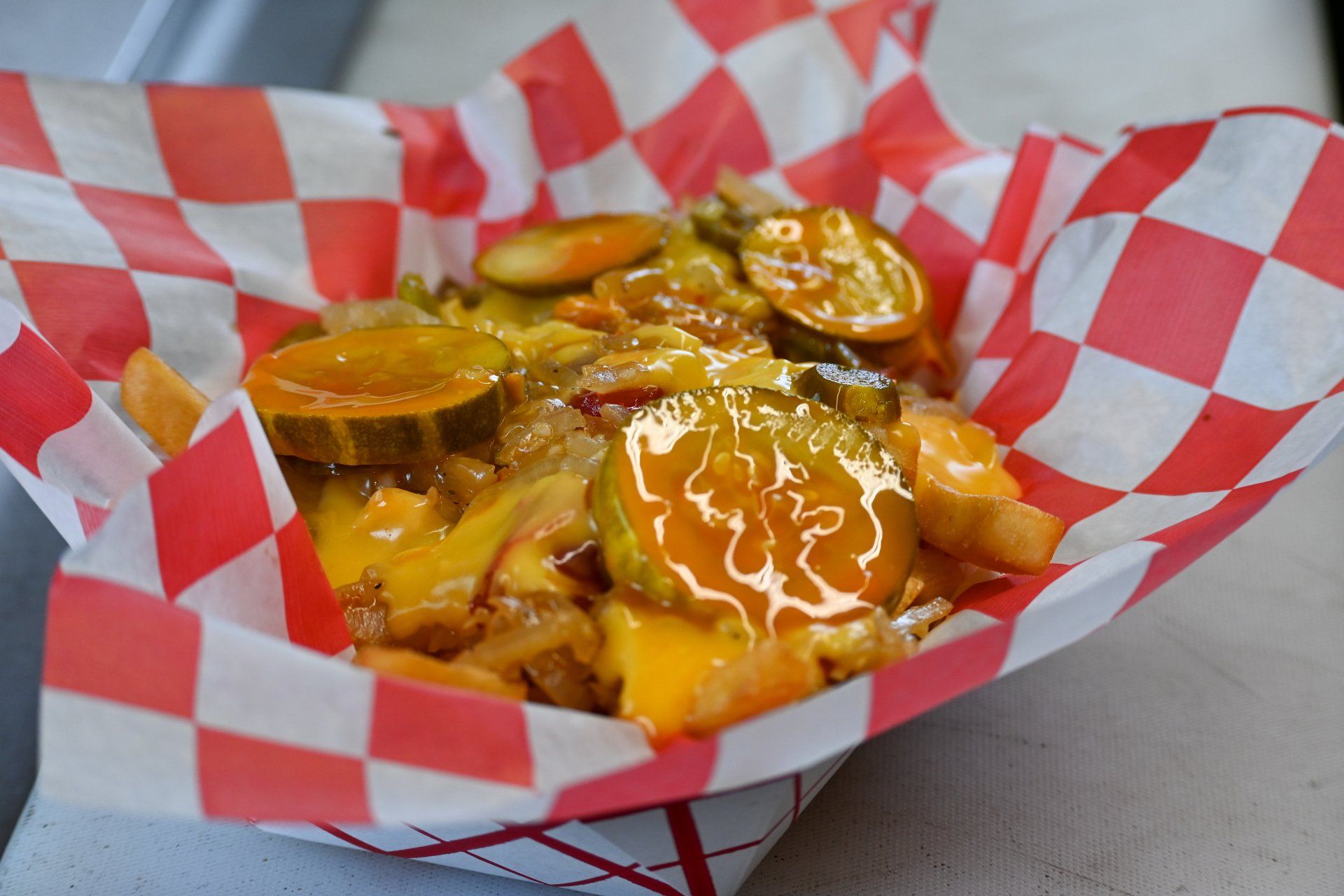 A basket of french fries and pickles on checkered paper