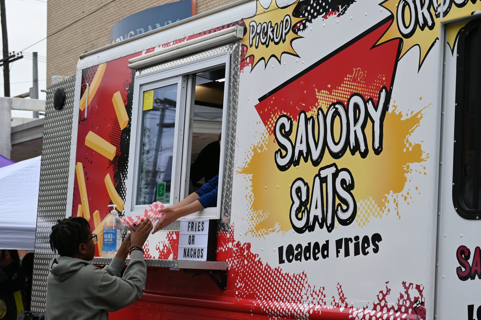 A woman is getting food from a savory cats food truck