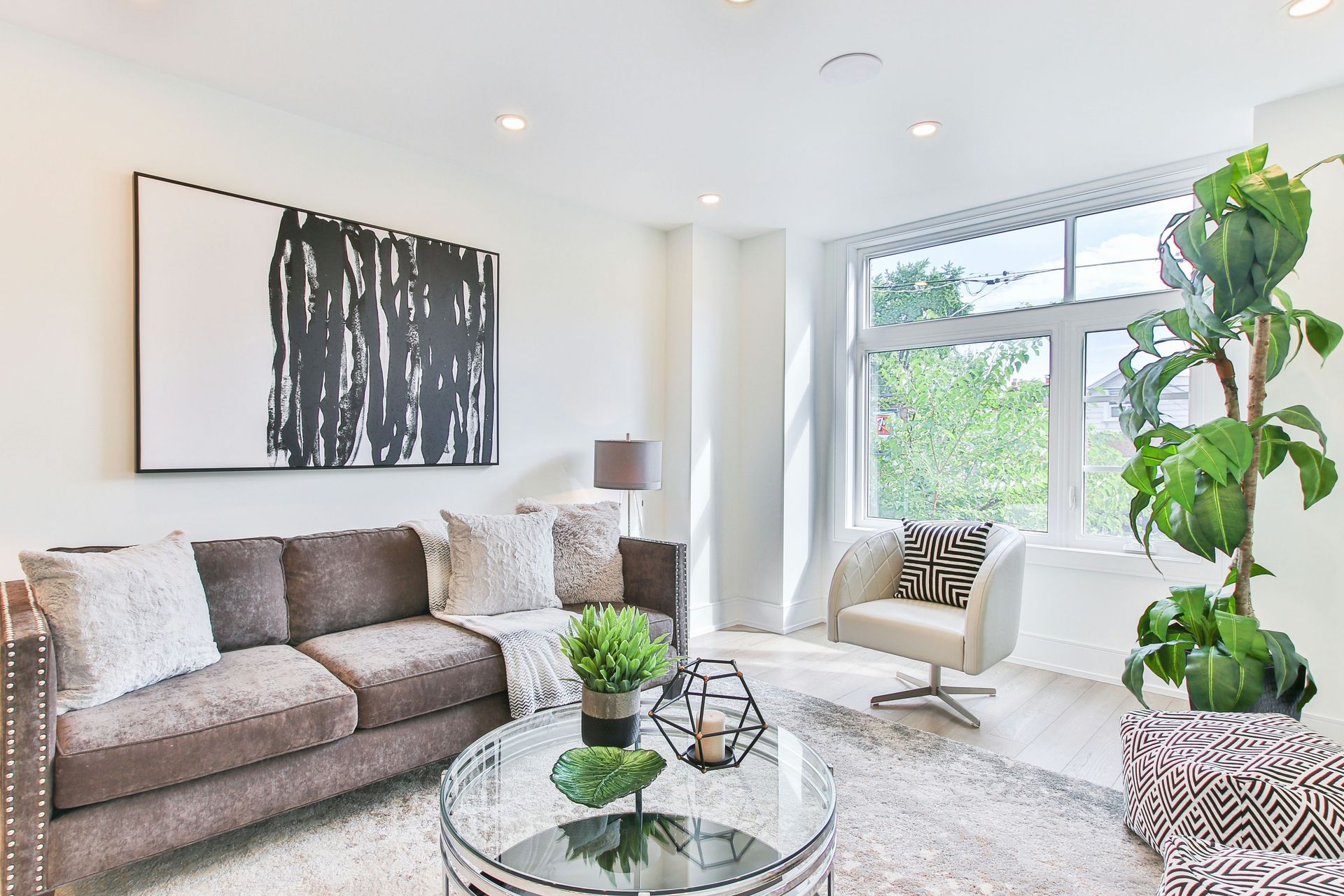 a living room with a couch , chair , coffee table and plant .