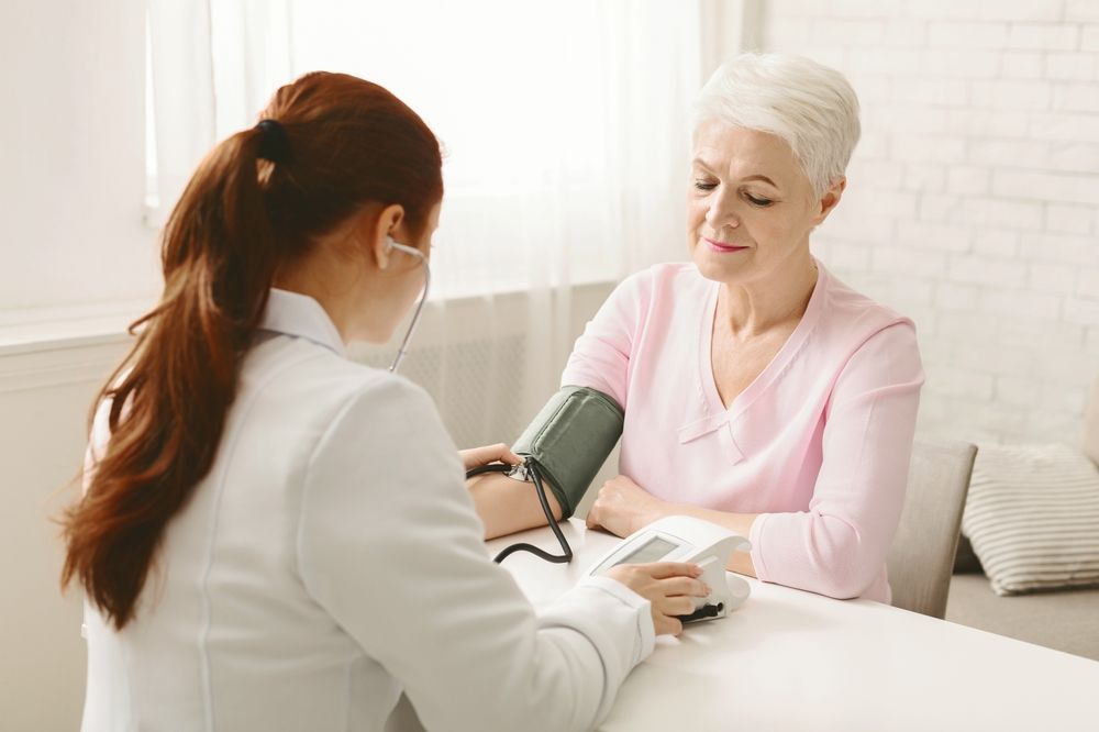 Doctor taking patient's blood pressure in a medical setting.