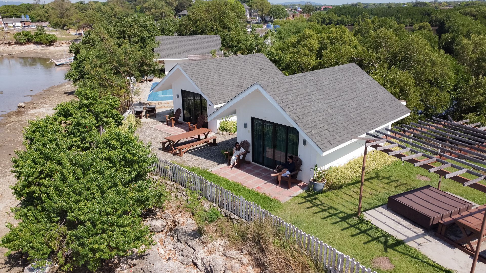 White cottages with gray roofs by a body of water and trees.