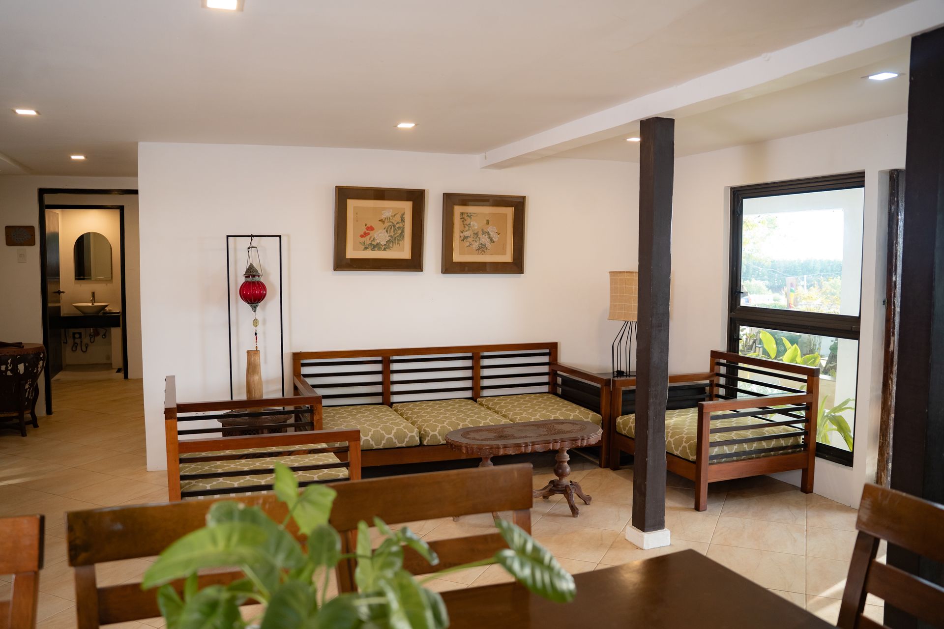Living room with wooden furniture, white walls, and a large window.