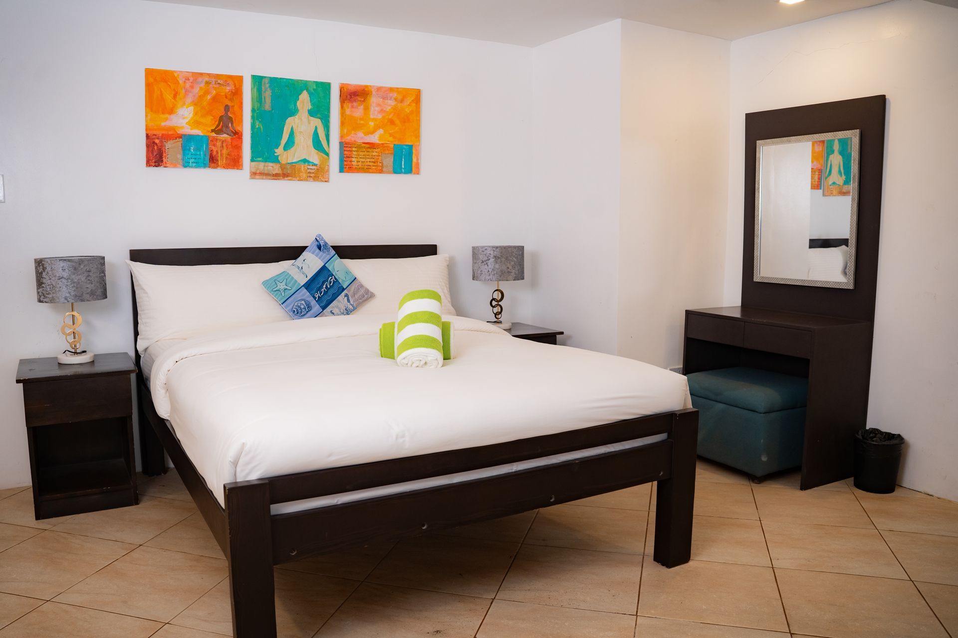 Bedroom with a dark wooden bed, nightstands, and a vanity. Artwork hangs on the wall.