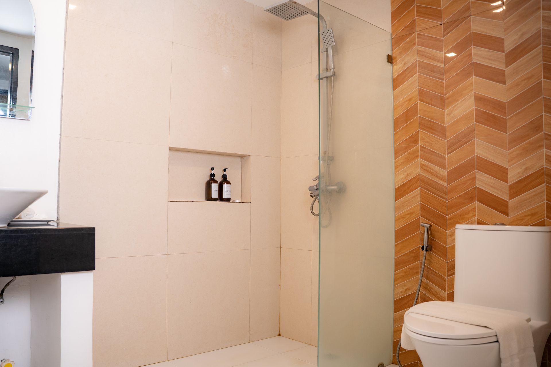 Bathroom with beige and brown tile, glass shower, and toilet.