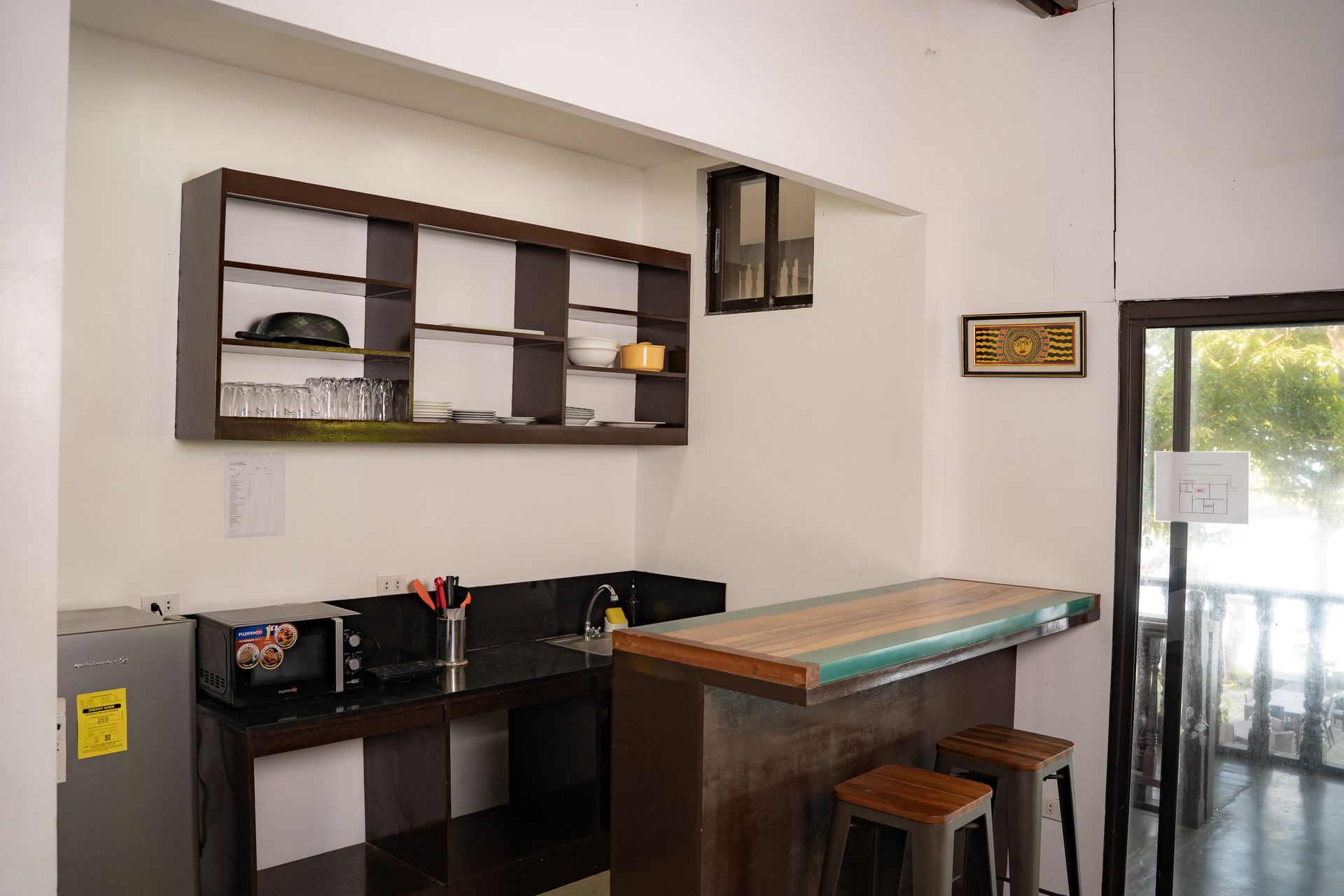 Small kitchen area with a bar, open shelving, and a refrigerator.