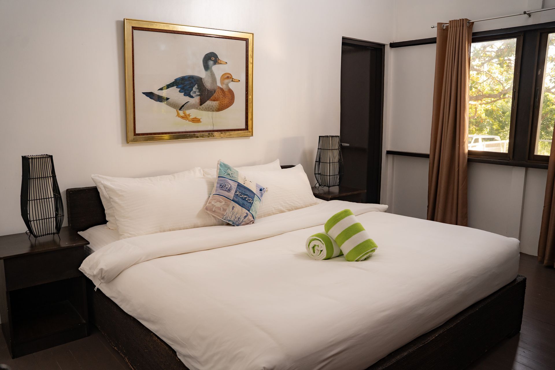 Bedroom with a bed, artwork of ducks, and a window with sunlight.