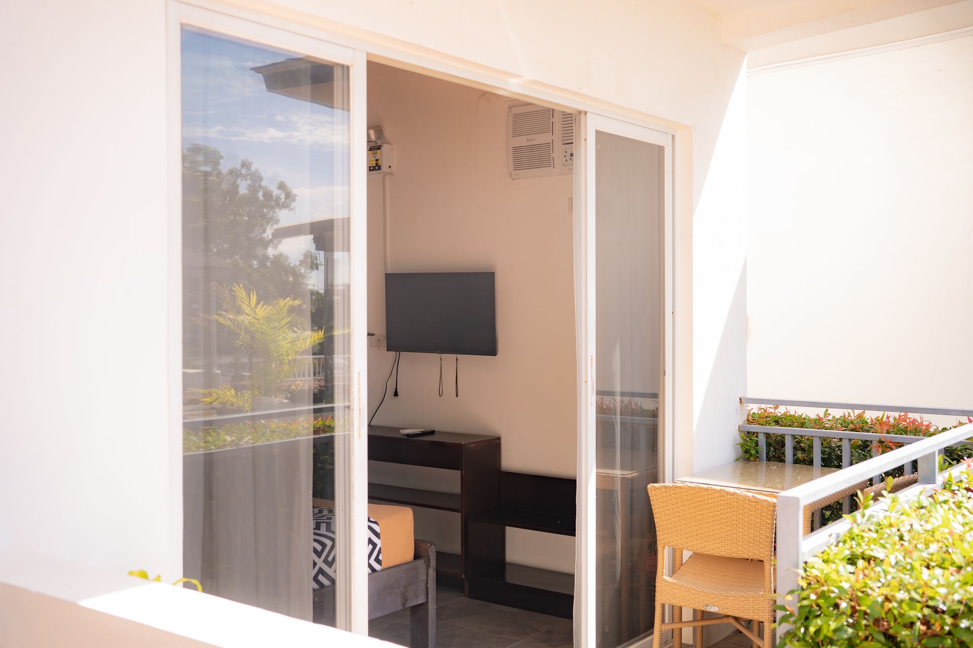 Sliding glass doors open to a balcony with a small TV and desk inside.
