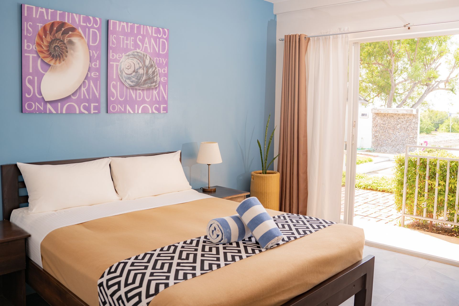 Bedroom with bed, blue wall, art, and patio door.