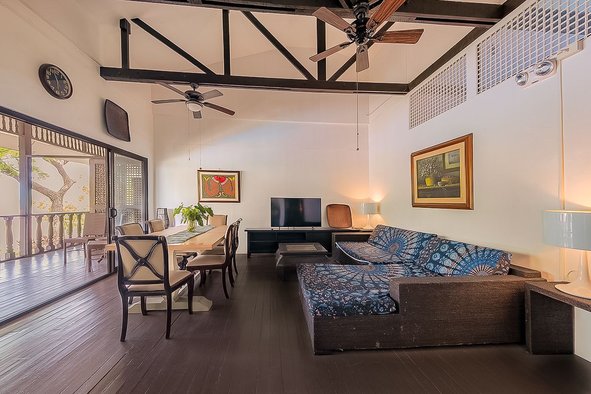 Spacious living room with dining area. Dark wood floors, white walls, and a patterned sofa.