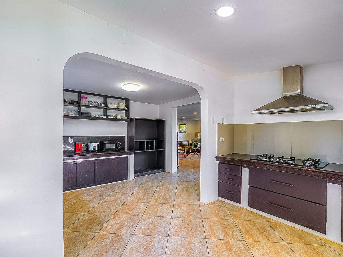 Kitchen with dark brown cabinets, tile floor, and stainless steel range hood.