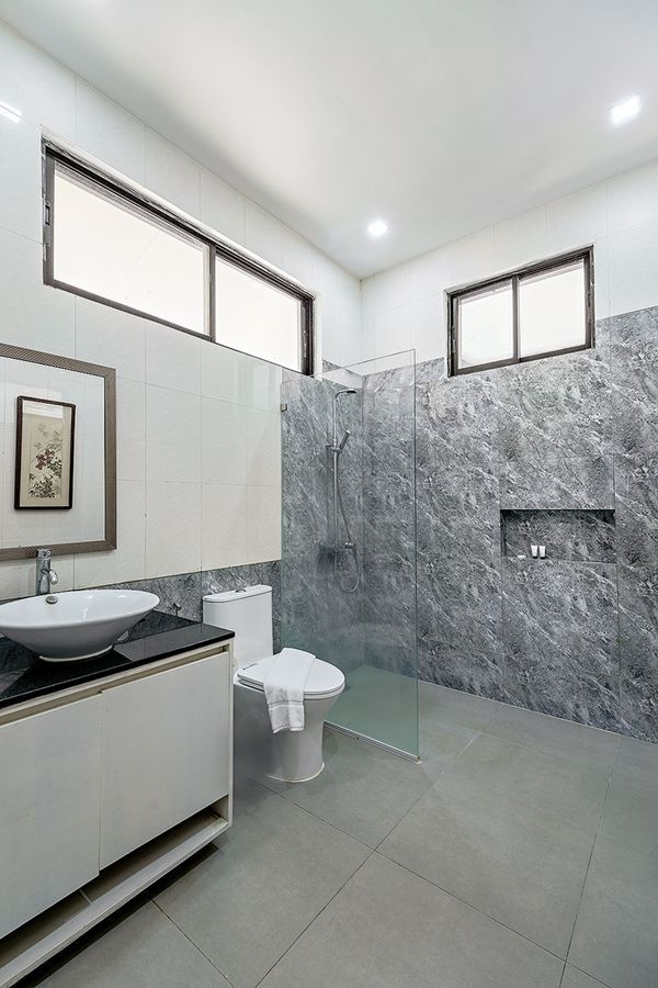 Modern bathroom with gray textured wall, vanity, toilet, and glass shower.