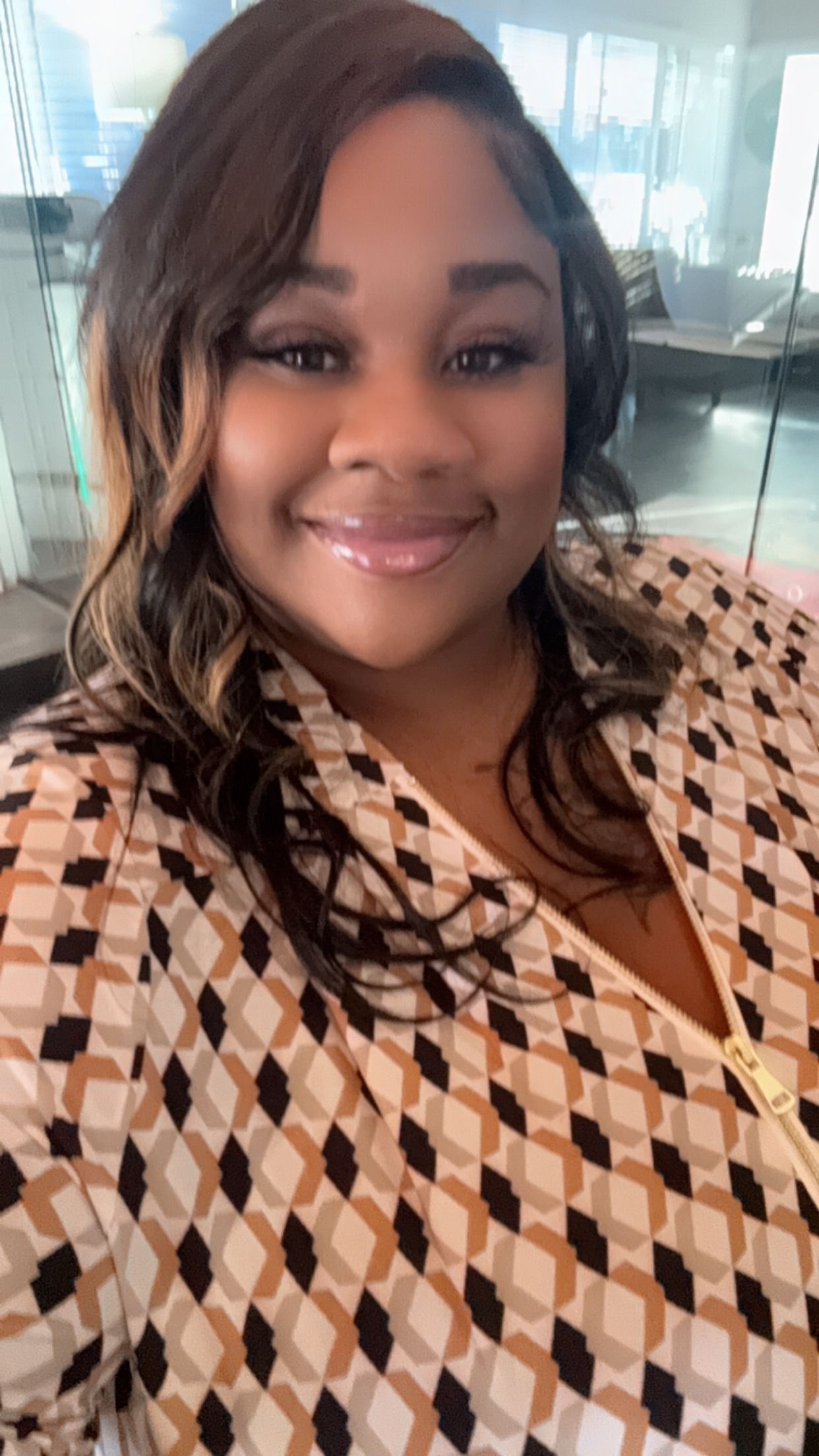 A woman is sitting at a desk with a laptop and a vase of flowers.