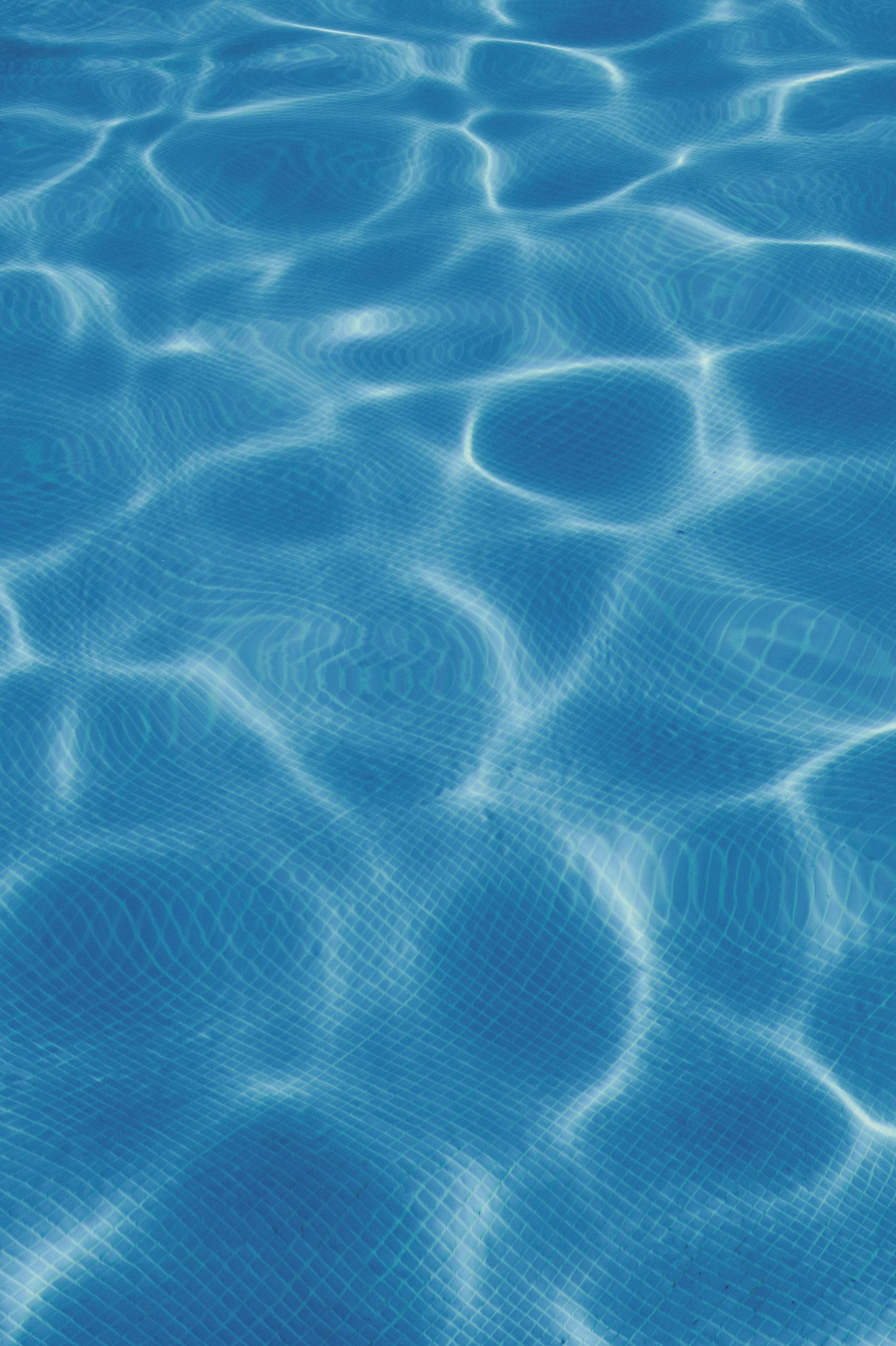 Sunlit blue swimming pool water with rippling reflections