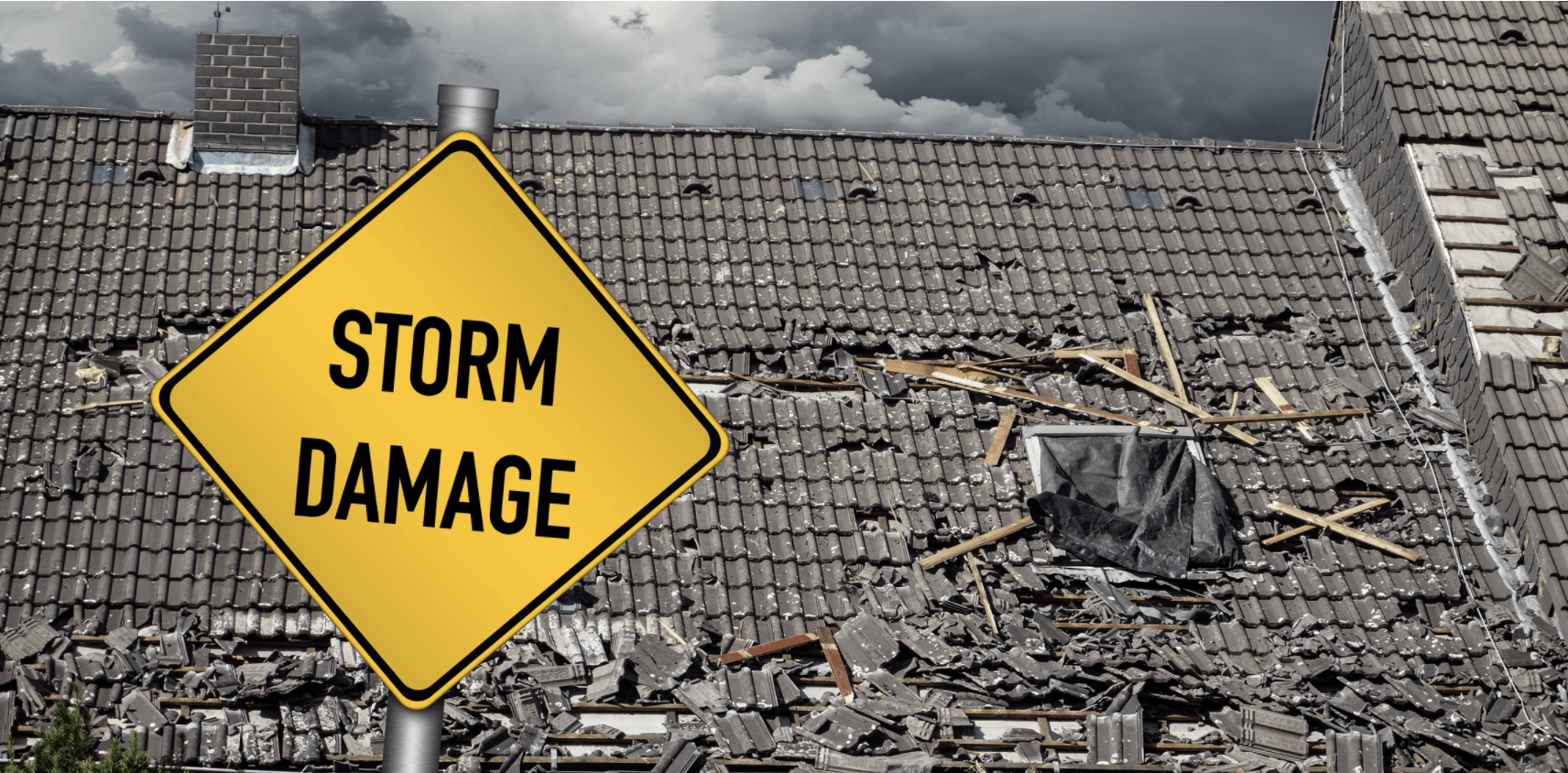 A yellow storm damage sign stands in front of a roof with significant damage under a stormy sky.