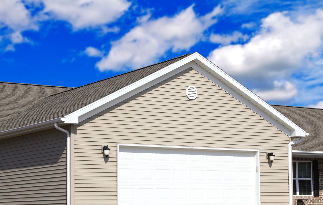 A house with a white garage door and a blue sky in the background.