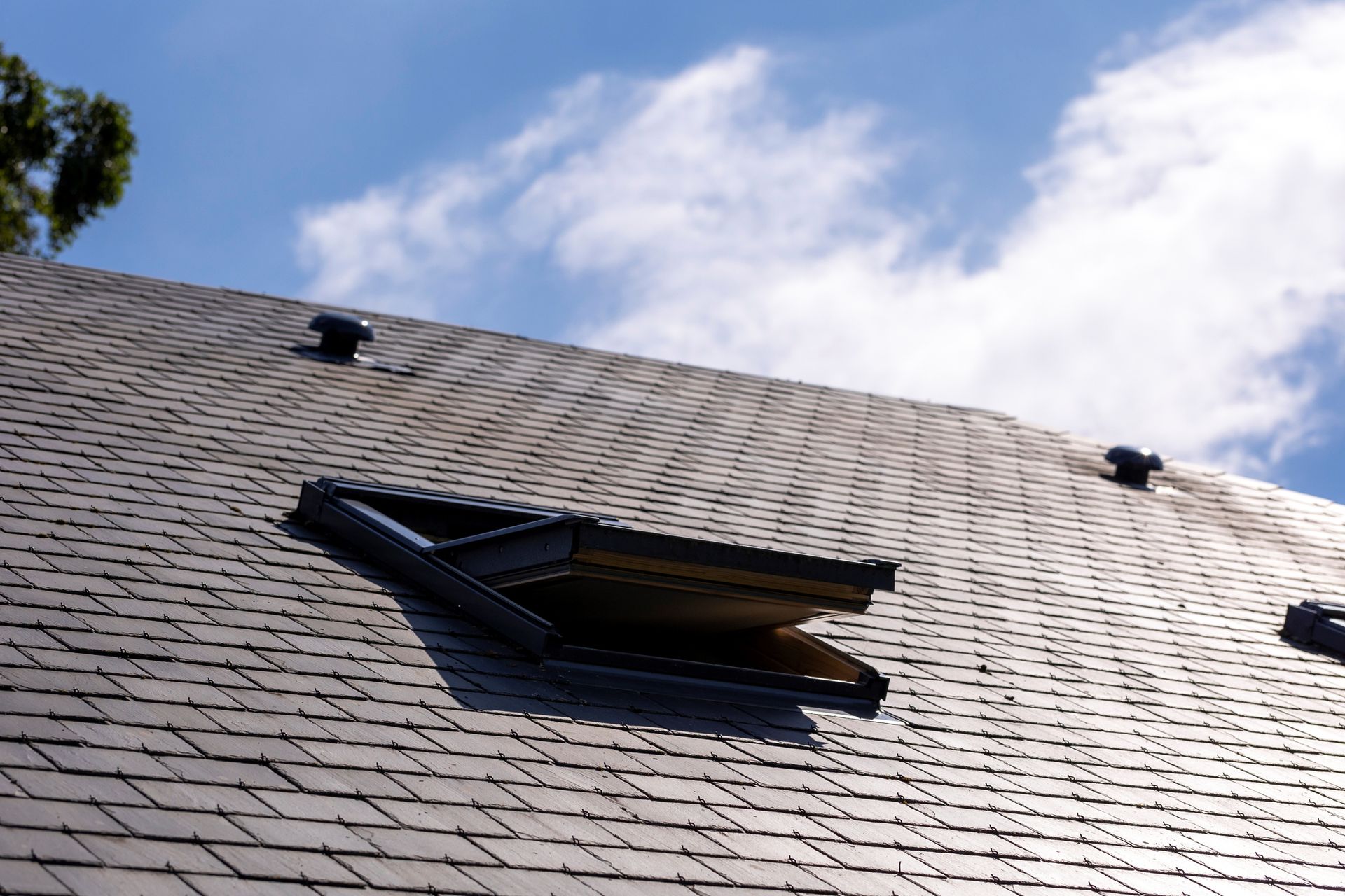 A roof with a skylight on it and a blue sky in the background