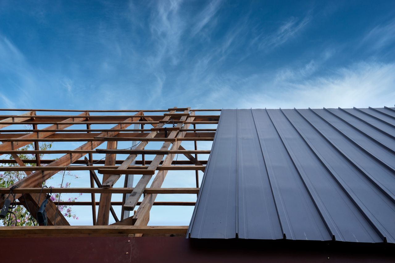 A metal roof is being installed on top of a wooden structure.