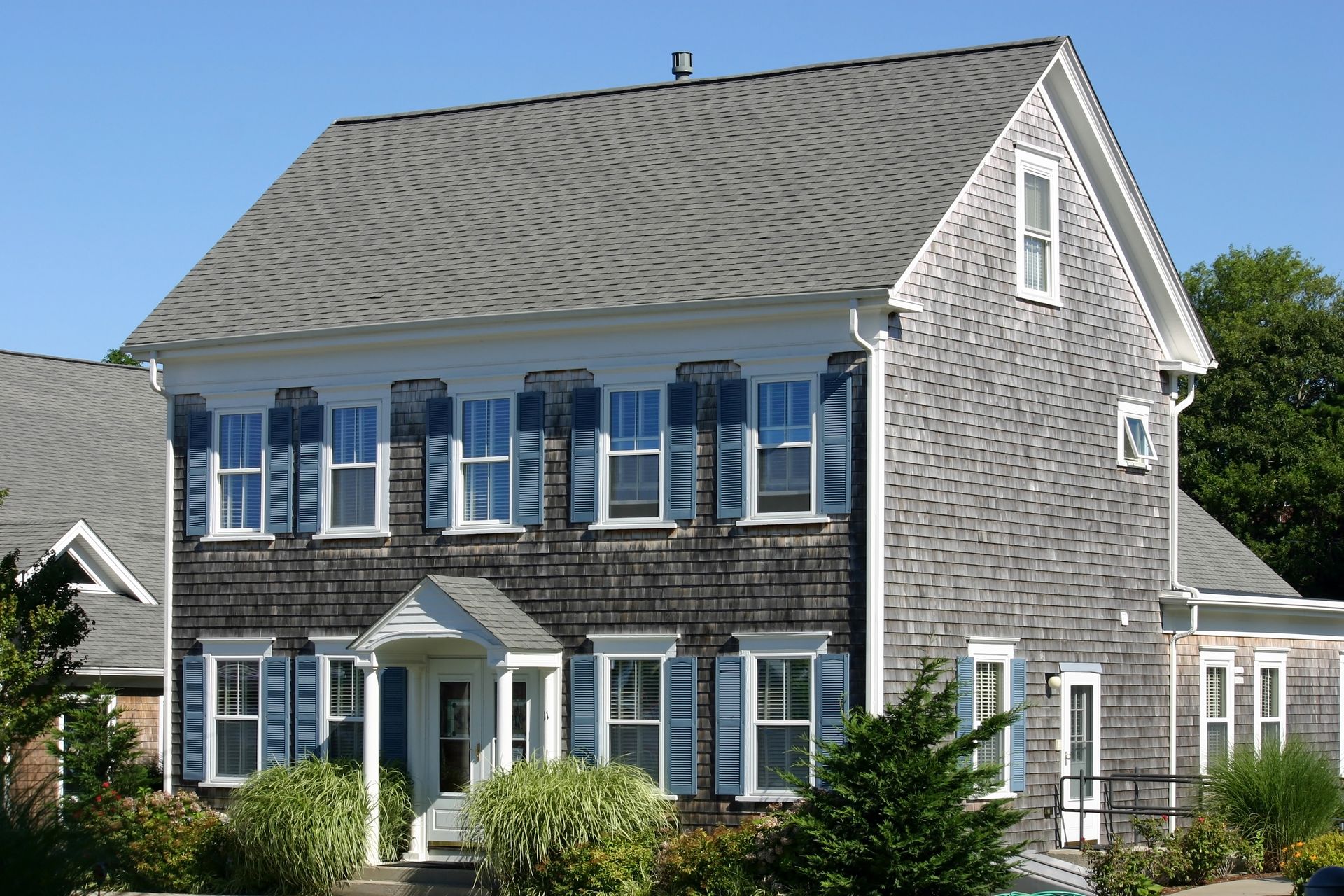 A large house with blue shutters and a gray roof