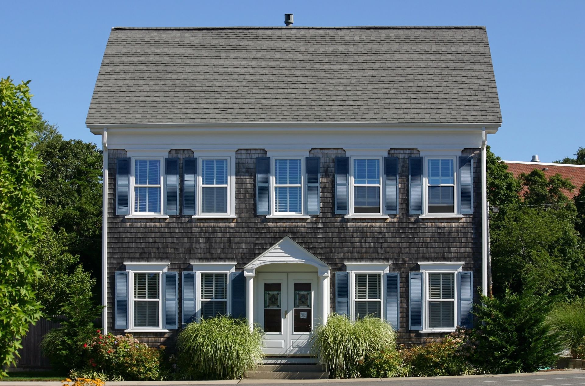 A large house with blue shutters and a gray roof