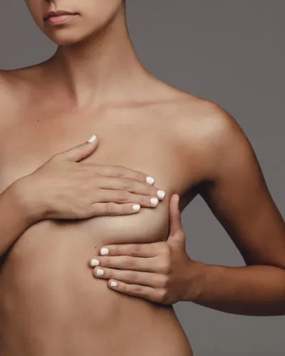 Person with hands covering chest against a plain gray background