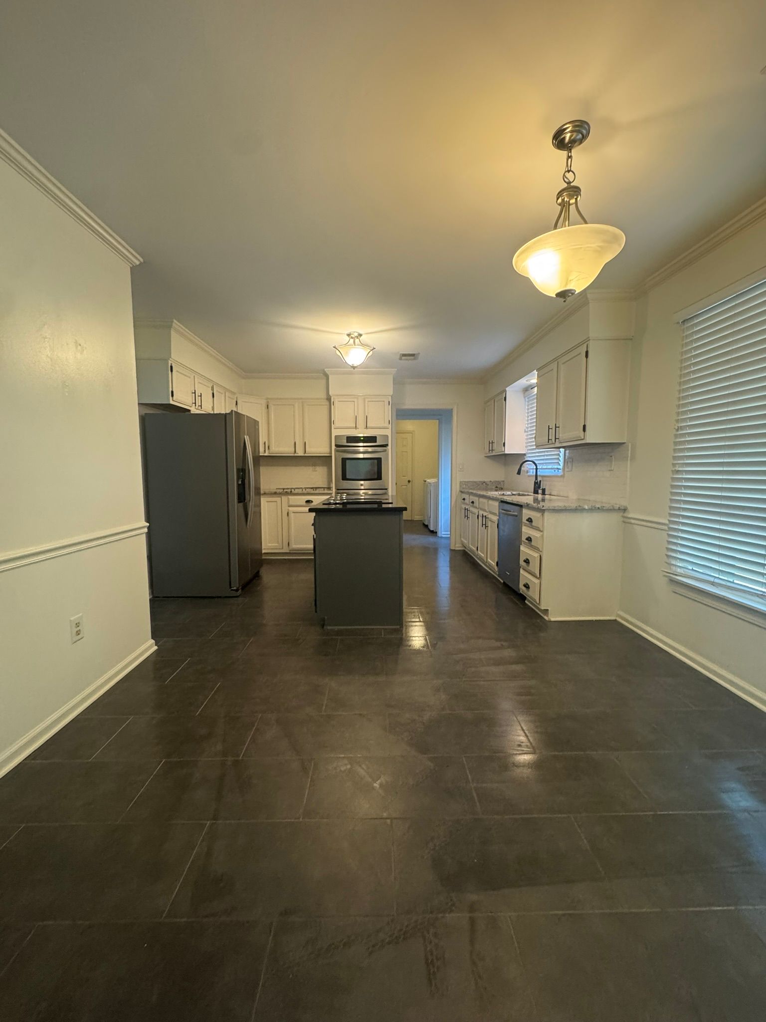 Open kitchen with white cabinets, gray island, and dark gray floors.