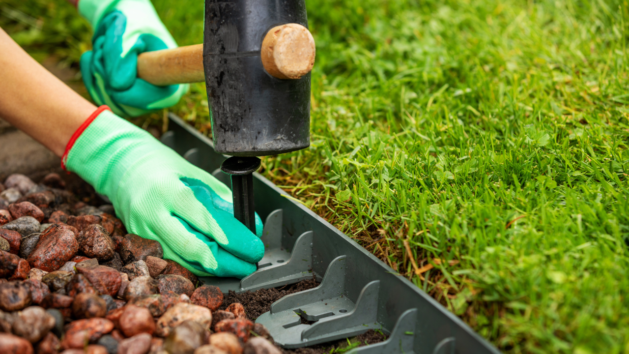 A person is using a hammer to install a lawn edging.