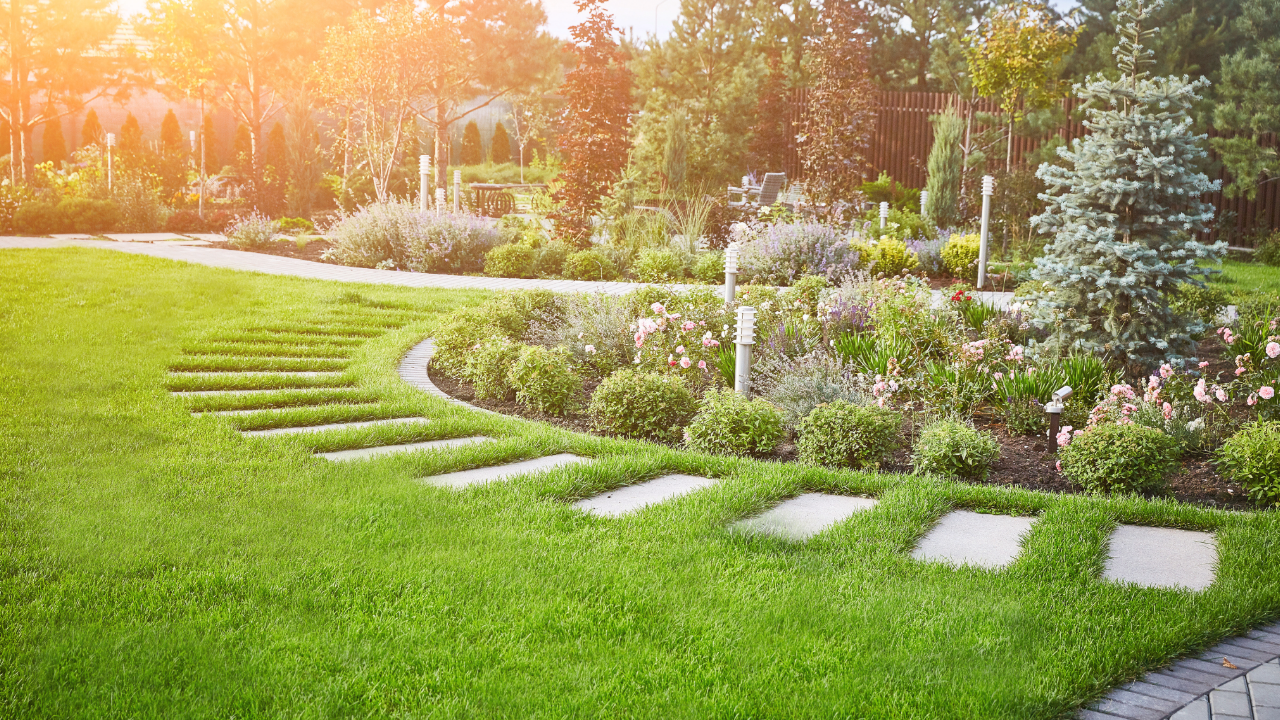 A lush green garden with a brick walkway leading through it.
