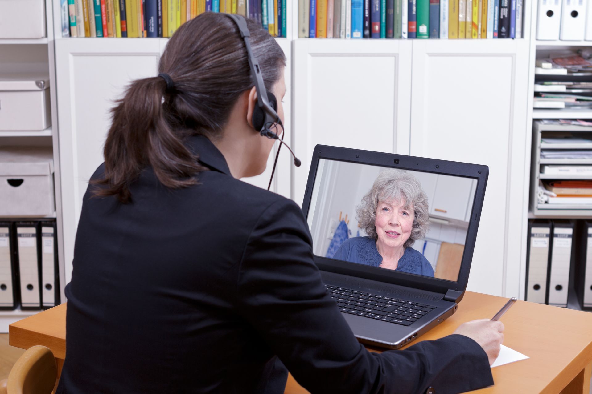 Video call between a headset user and a woman on a laptop in an office