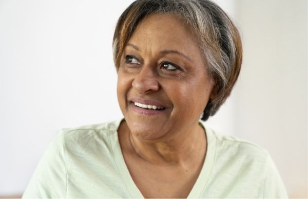 Smiling person looking to the side, wearing a light green shirt.